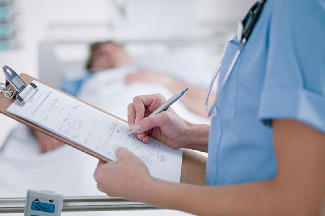 A medical professional writing on a hospital chart