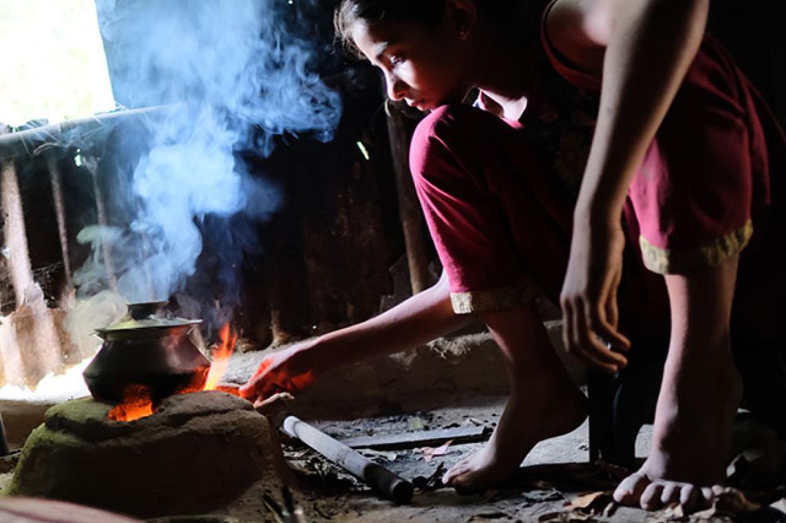 A young girl cooking over an open flame