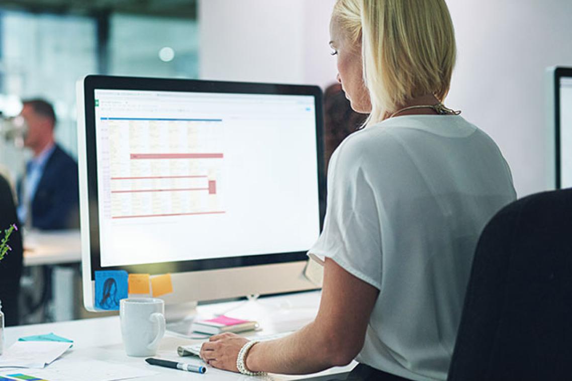 Office workers at their desk looking at computer monitor