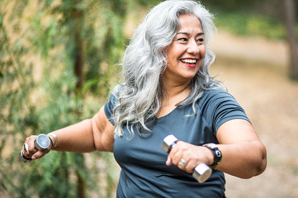 Woman holding weights while exercising outside 