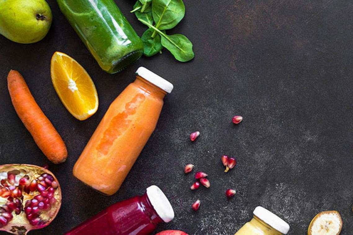 Fruits and vegetables surrounded by bottles of juices and smoothies