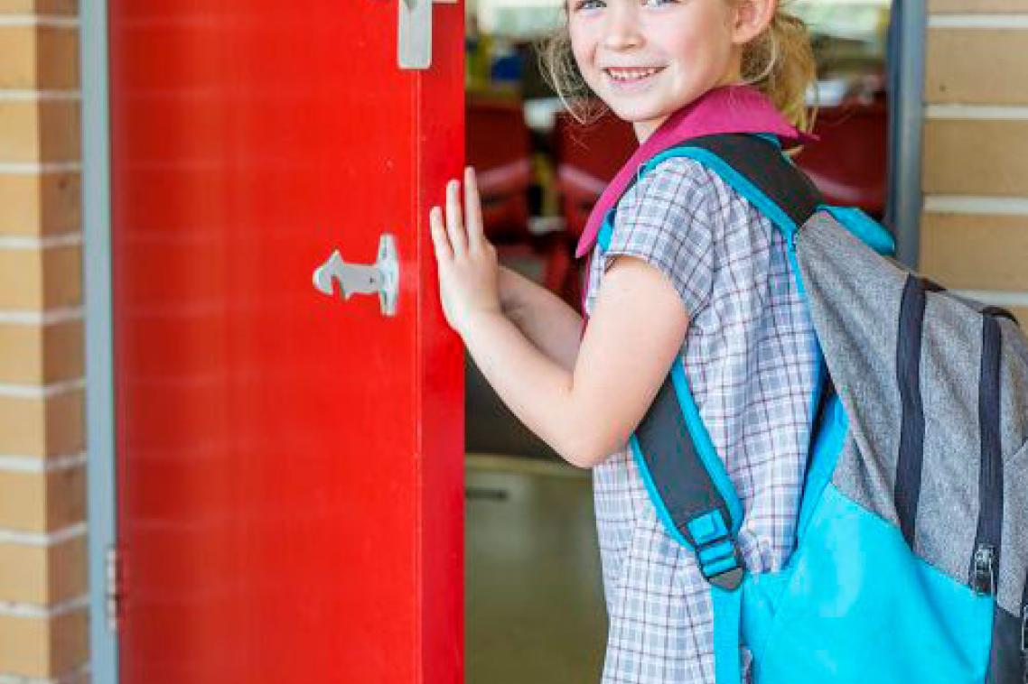 A primary school girl entering a classroom, looking back over her shoulder