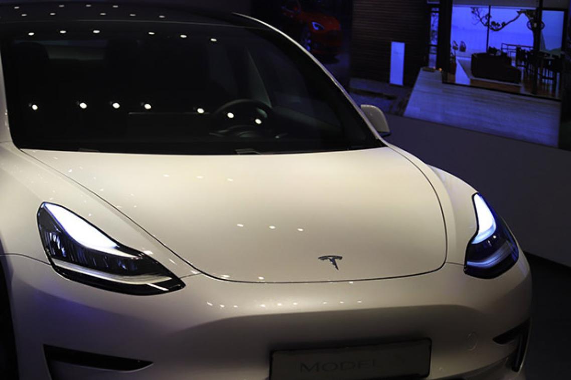 A futuristic Tesla car sits in a showroom with blue lights in the background