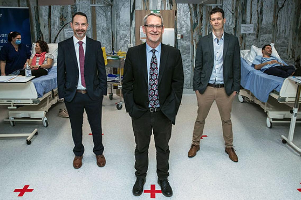 Professor Trent Munro, Professor Paul Young and Assistant Professor Keith Chappell stand in the clinic with the first participants of the Phase I clinical trial of the UQ COVID-19 vaccine.
