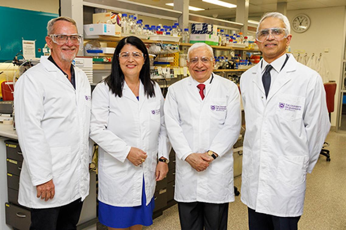 Four smiling people wearing safety equipment in a laboratory